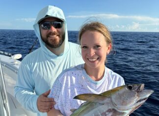 a man and a woman on a boat holding a fish
