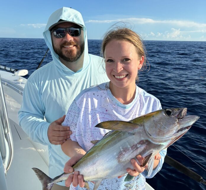 a man and a woman on a boat holding a fish