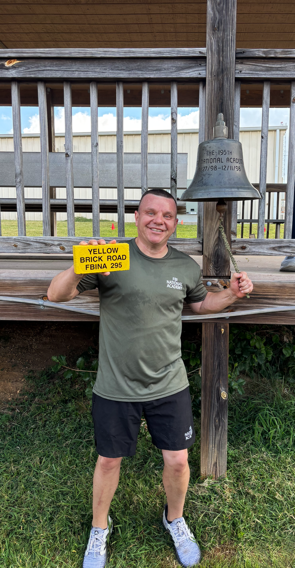 a man standing in front of a bench with a bell on it