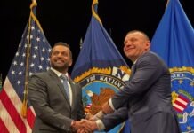 two men shaking hands in front of flags