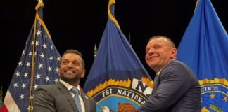 two men shaking hands in front of flags