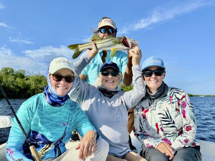 F. Anglers with fish three people on a boat holding up a fish