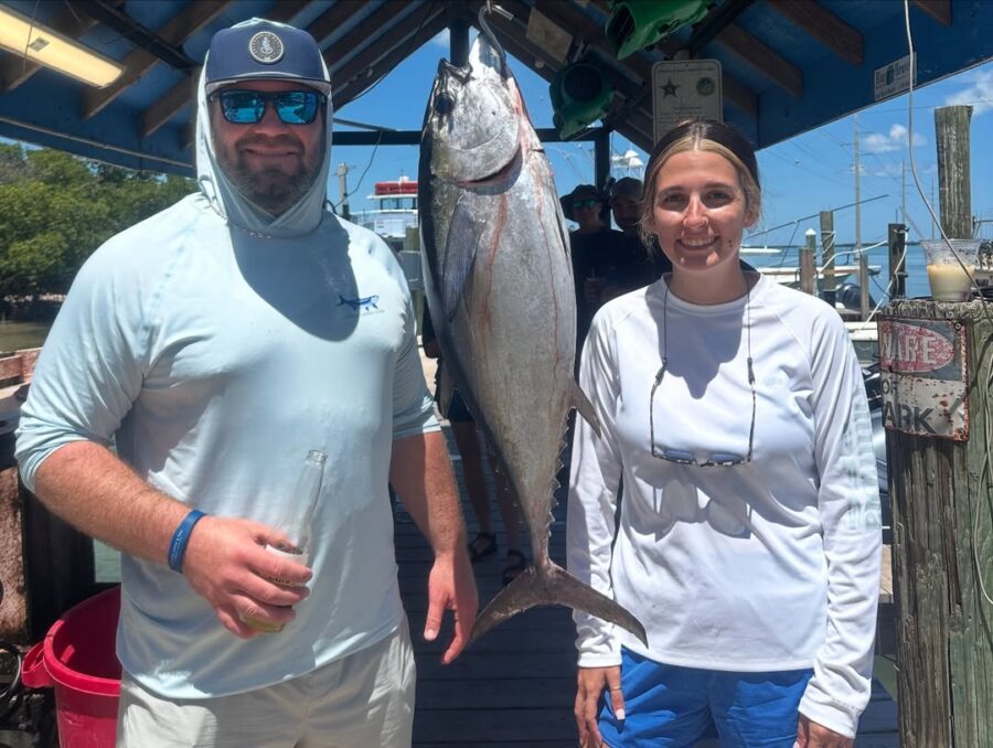 a man and a woman standing on a dock holding fish