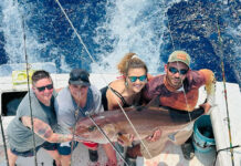a group of people on a boat holding a fish