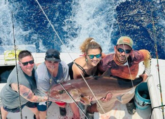 a group of people on a boat holding a fish