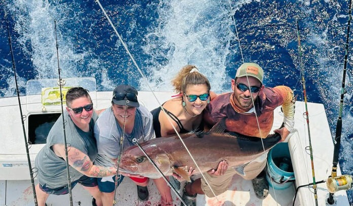 a group of people on a boat holding a fish