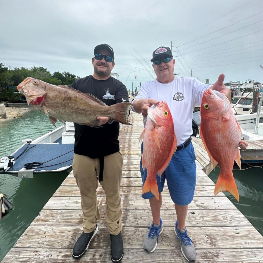 two men standing on a dock holding fish