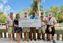 a group of people standing next to each other holding a large check