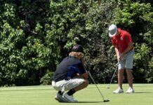 a man kneeling down to put a golf ball on the green