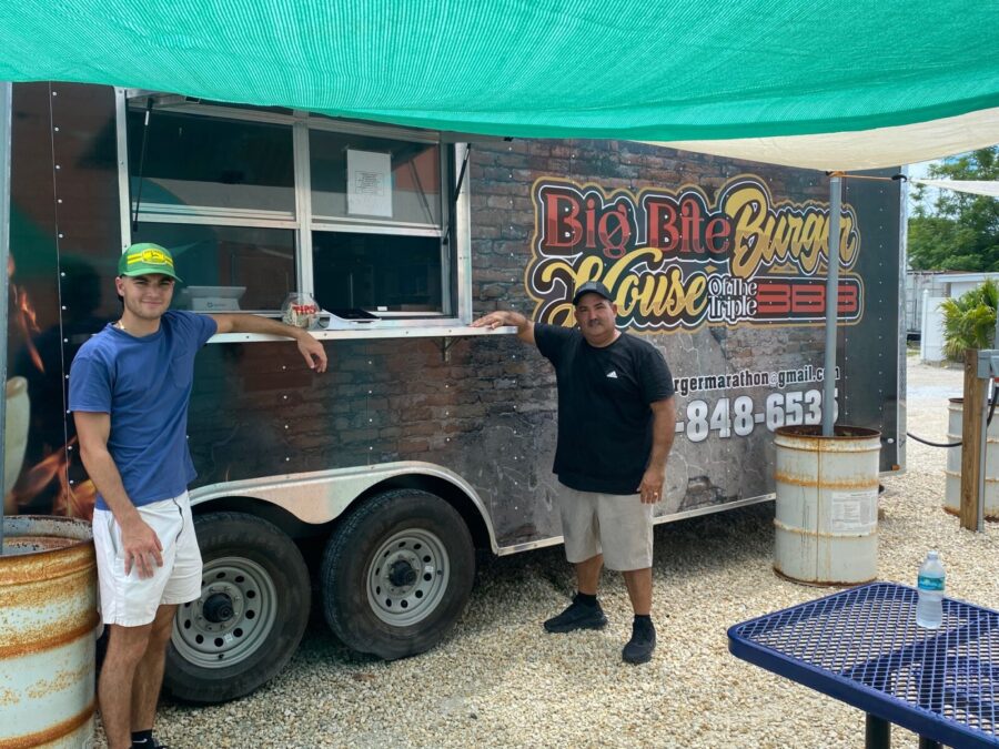 two men standing in front of a food truck