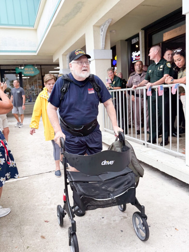 a man pushing a stroller down a sidewalk next to a crowd of people