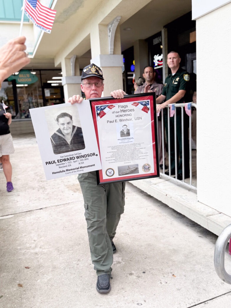 a man holding a framed picture of a man in uniform