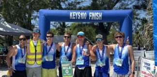 a group of people standing on top of a sandy beach
