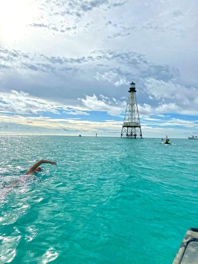 a person swimming in the ocean next to a light house