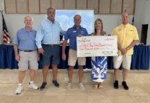 a group of people standing around a table holding a check