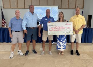 a group of people standing around a table holding a check