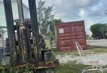 a chair sitting in the grass next to a forklift