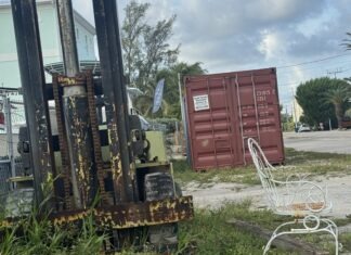 a chair sitting in the grass next to a forklift