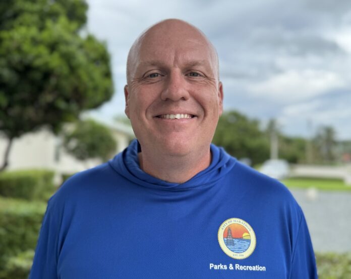 a man in a blue shirt standing in front of a lake