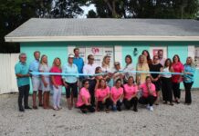 a group of people in pink shirts holding a ribbon