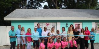 a group of people in pink shirts holding a ribbon