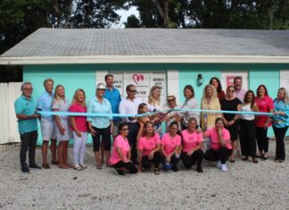 a group of people in pink shirts holding a ribbon