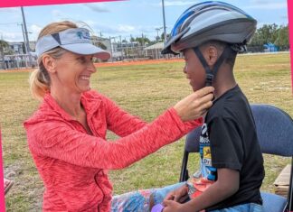 a woman helping a young boy with a helmet