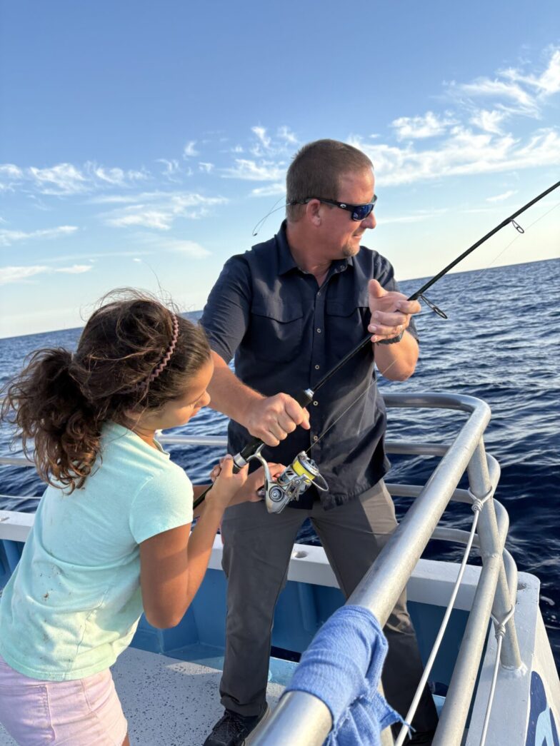 a man and a little girl fishing on a boat