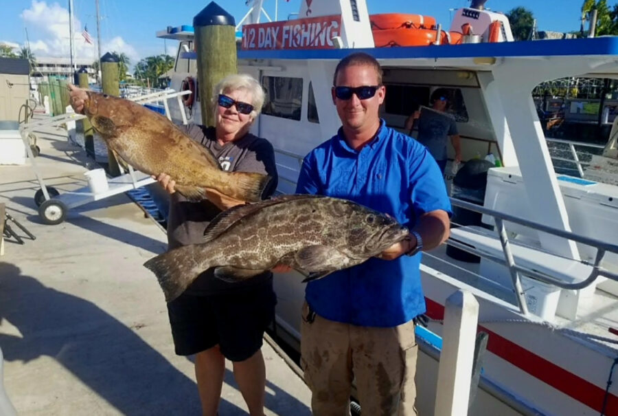 a man and a woman holding a large fish