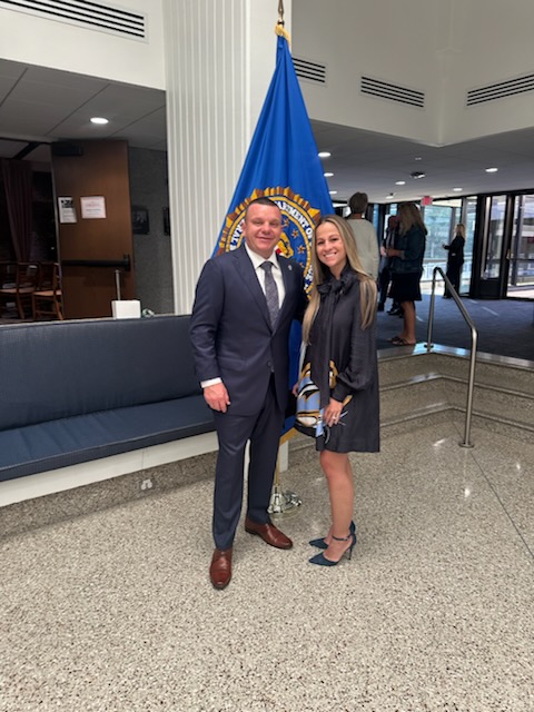 a man and a woman standing in front of a flag