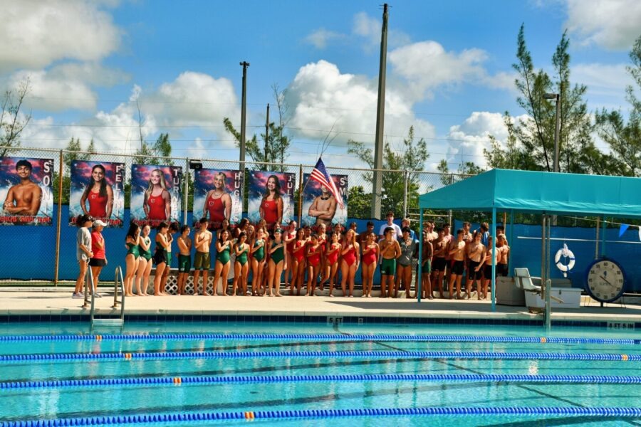 a group of people standing next to a swimming pool