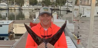a woman holding a fish on a dock