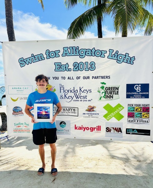 a man standing in front of a sign on the beach