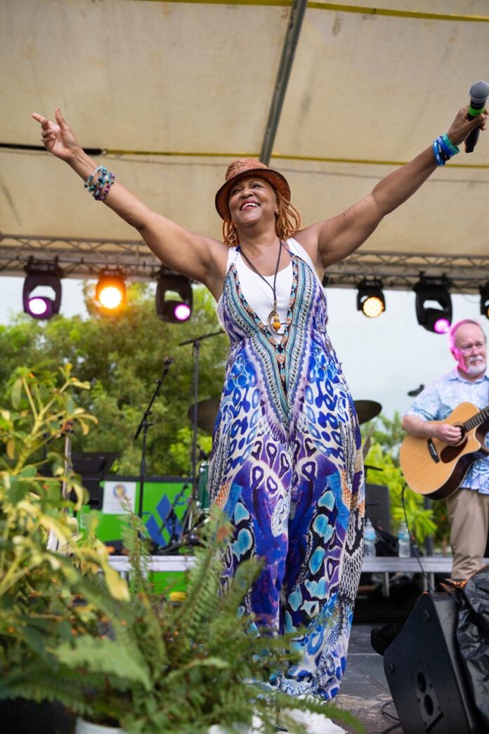 a woman in a colorful dress and hat on stage