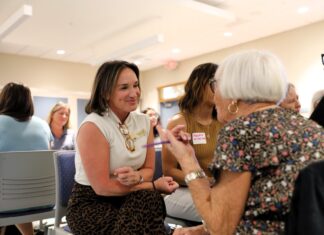 a group of women sitting in chairs talking to each other