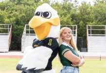 a woman standing next to a large bird mascot