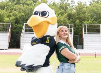 a woman standing next to a large bird mascot