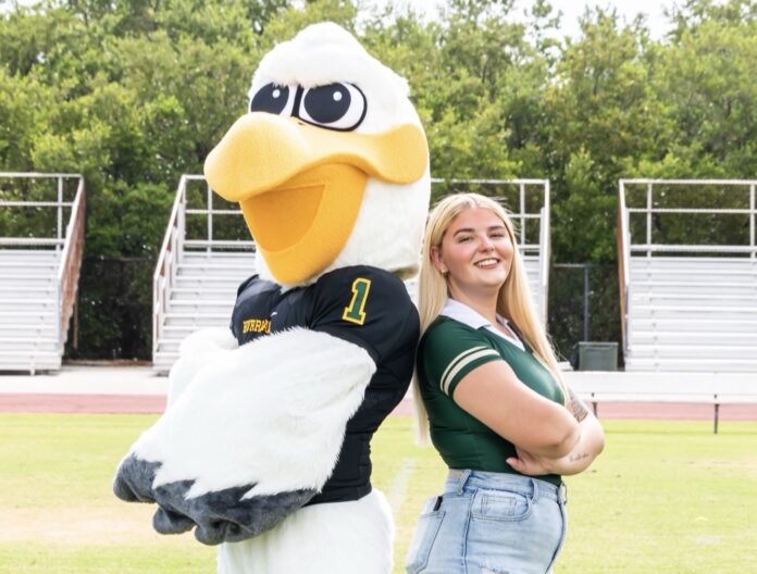 a woman standing next to a large bird mascot