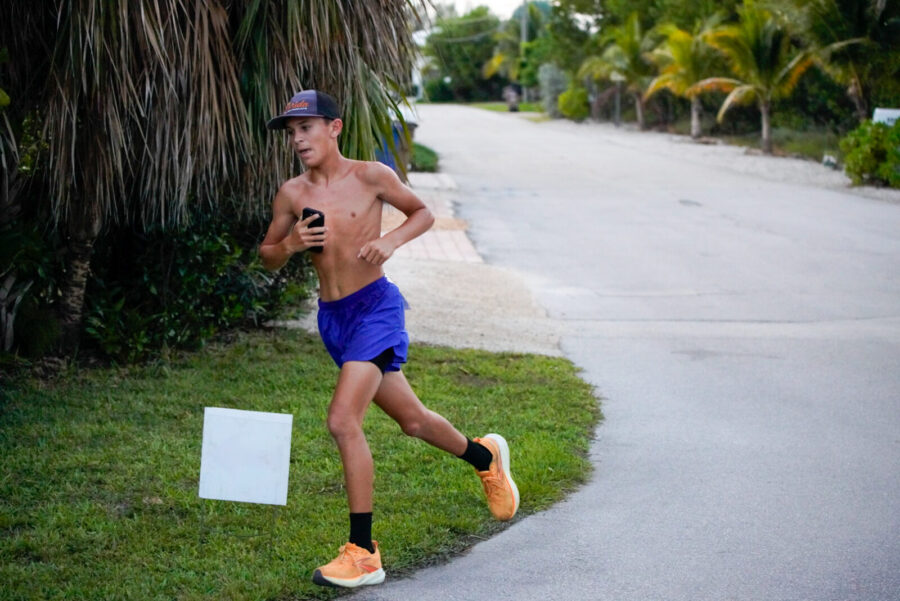 a man running down a street next to a palm tree