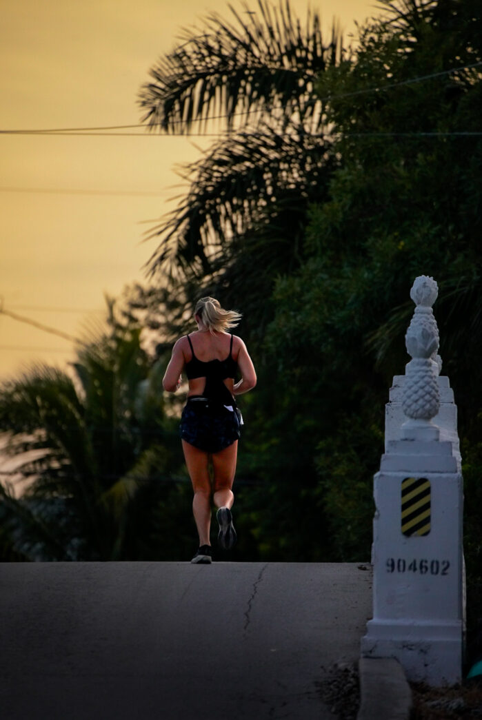a woman running down a street at sunset
