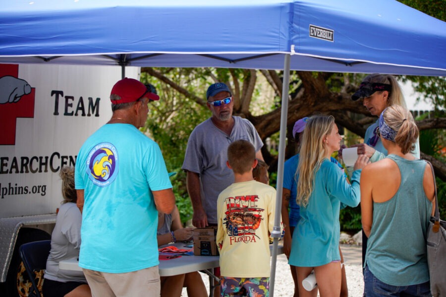 a group of people standing under a blue tent
