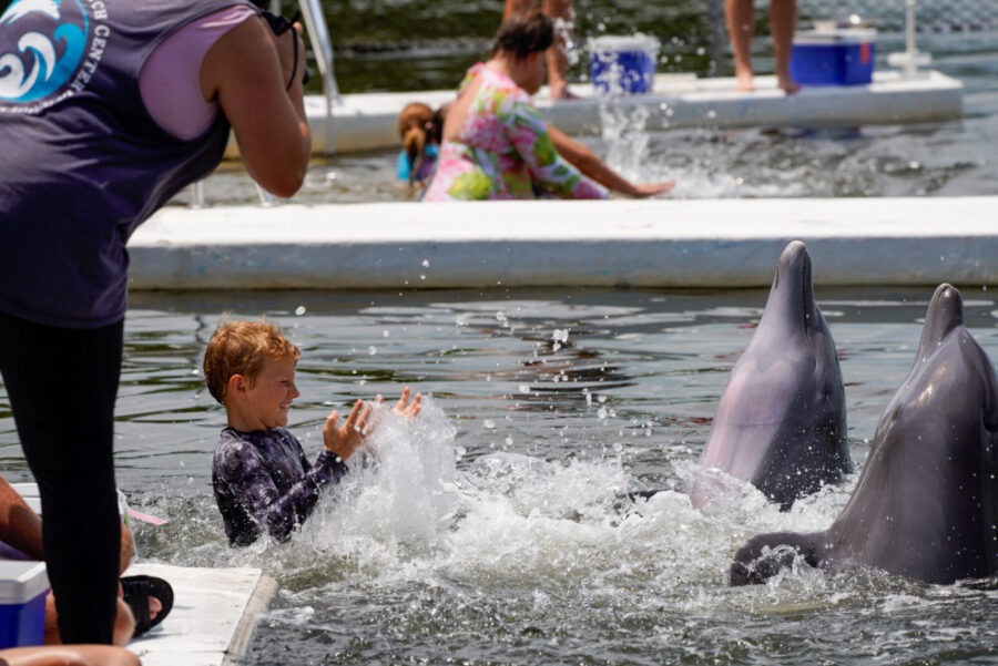 a woman standing next to a boy in a pool of water