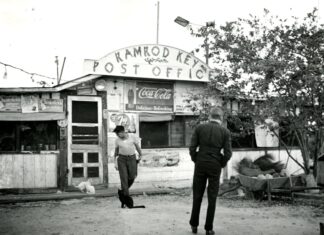 a black and white photo of a man and a woman walking in front of a