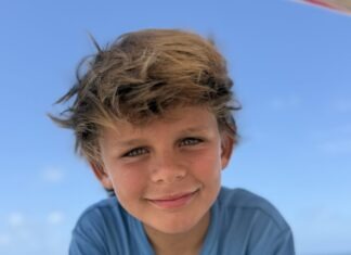 a young boy sitting on a beach next to the ocean