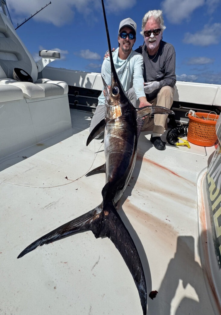 a man and a woman holding a fish on a boat