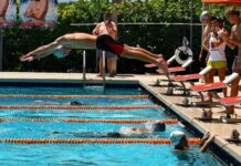 a man diving into a swimming pool while people watch