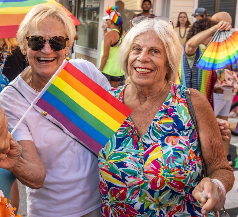 a couple of women standing next to each other holding a rainbow flag