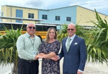 two men and a woman standing in front of a school bus