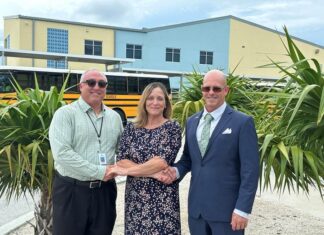 two men and a woman standing in front of a school bus
