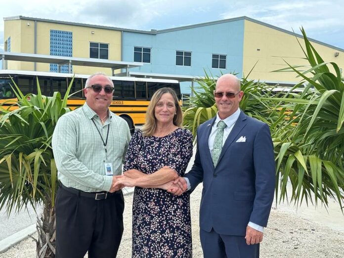 two men and a woman standing in front of a school bus